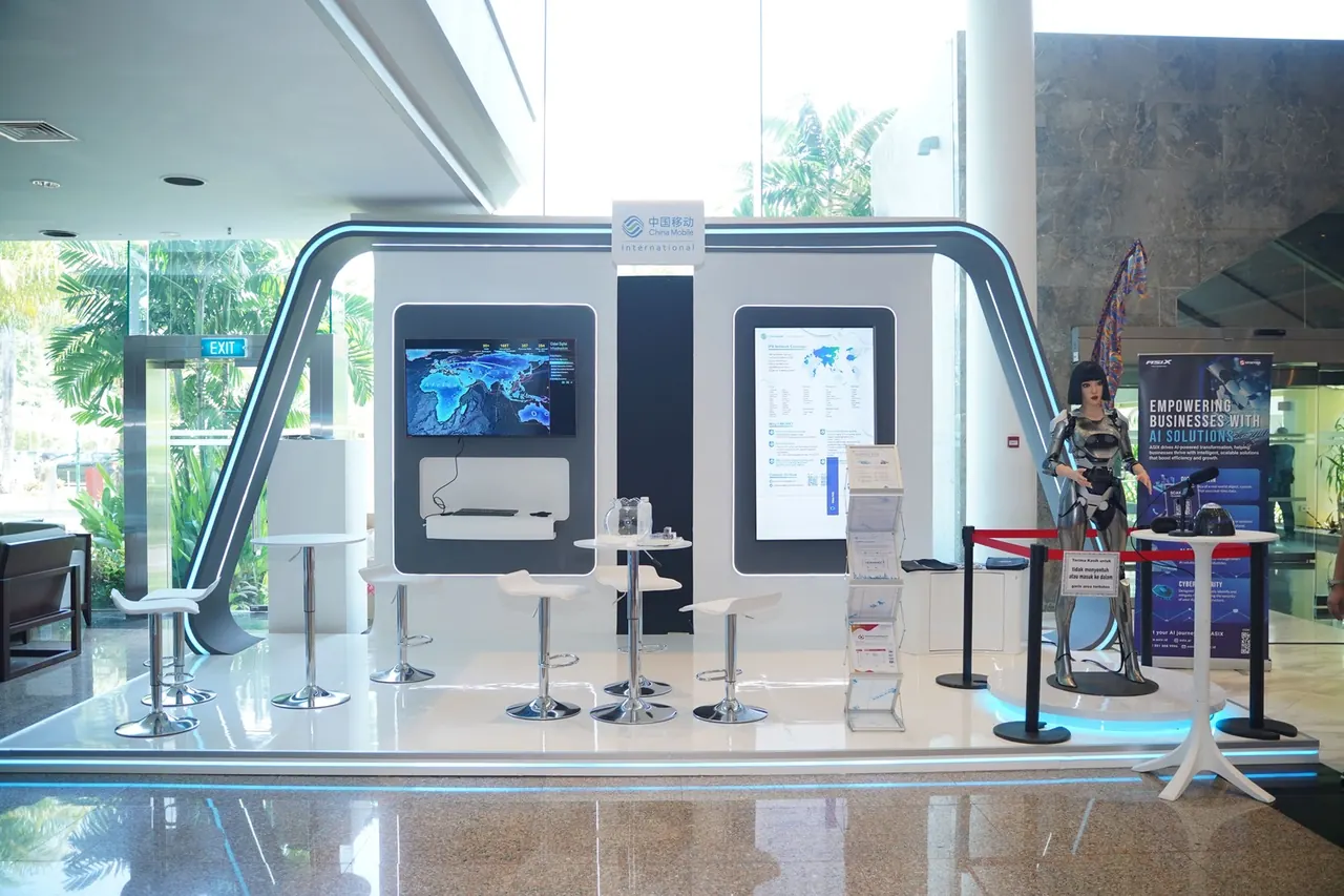 China Mobile International booth with two display screens, white stools and a humanoid robot host