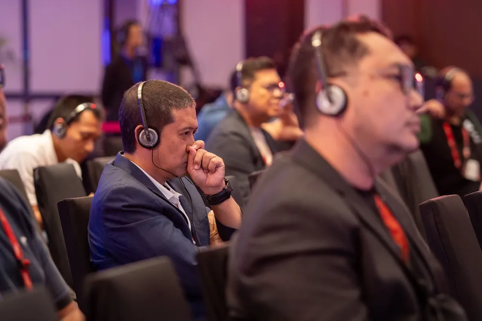 Delegates in headsets listening attentively to a session